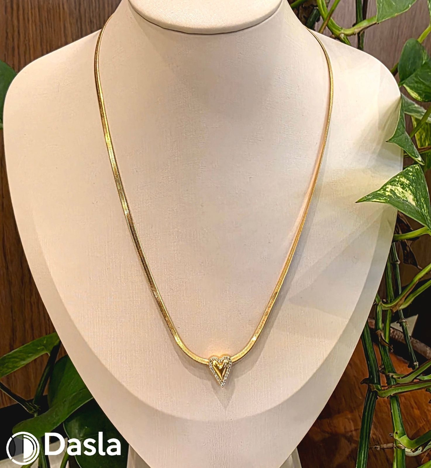 Colar dourado com pingente de coração em um busto de exposição